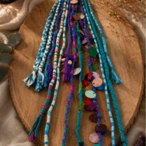 Handcrafted boho hair wrap accessory featuring turquoise, blue, and purple yarns with colorful metallic sequins and beads.